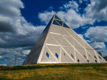 Built structure on field against cloudy sky