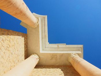 Low angle view of cropped built structure against clear blue sky