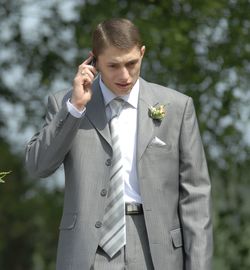 Bridegroom talking on mobile phone while standing outdoors