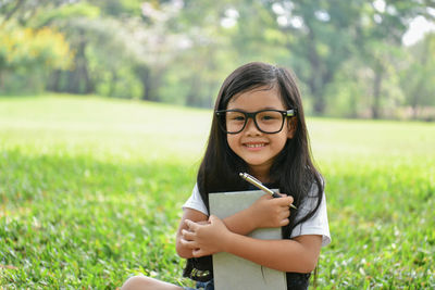 Portrait of woman holding book on field