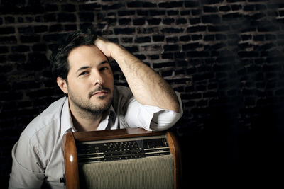 Portrait of man with radio against brick wall