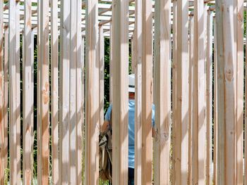 Rear view of person seen through wooden fence