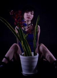 Midsection of woman holding flower against black background