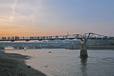 Bridge over river against sky during sunset