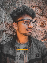 Portrait of young man standing against wall