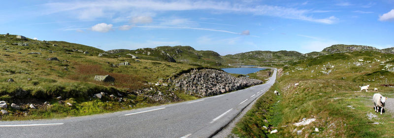 Road by field against sky