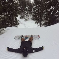 Man lying in snow with snowboard
