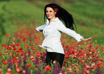 Portrait of smiling young woman standing against plants