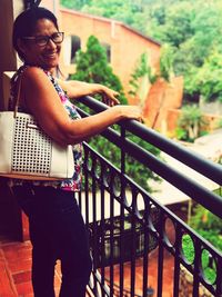 Portrait of smiling woman standing by railing