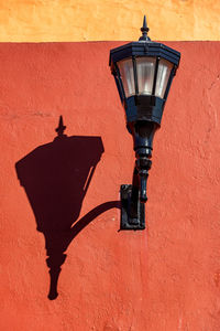 Low angle view of lamp post on wall during sunny day