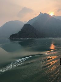 Scenic view of sea and mountains against sky during sunset
