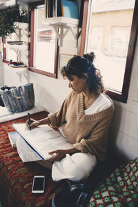 Woman sitting on book at home