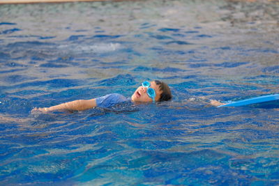 Portrait of boy lying in swimming pool