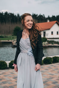 Portrait of smiling young woman standing against river