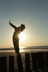 Silhouette man standing at beach during sunset