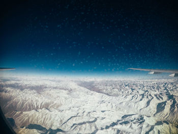 Scenic view of snowcapped mountains against clear blue sky at night