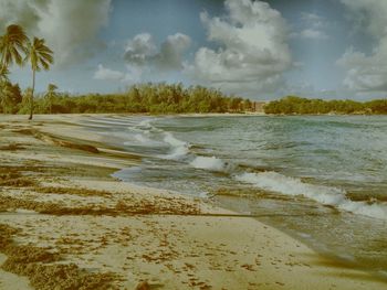 Scenic view of beach against cloudy sky