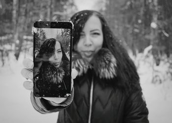 Portrait of woman holding camera outdoors