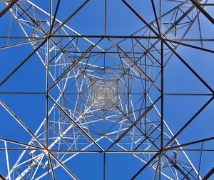 Low angle view of electricity pylon against blue sky