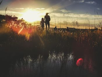 Silhouette people standing on field against sky during sunset