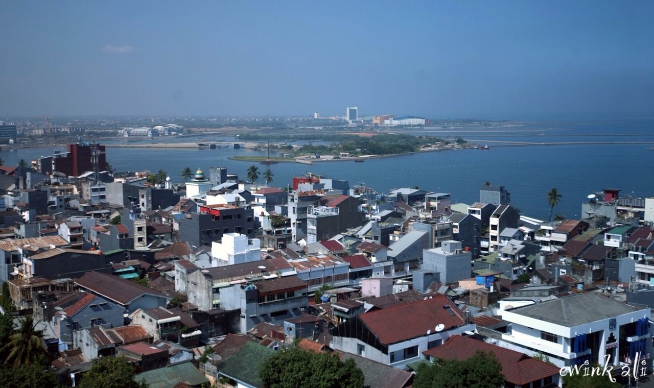 building exterior, architecture, built structure, sea, high angle view, residential district, water, residential structure, cityscape, crowded, city, town, house, townscape, residential building, blue, horizon over water, roof, sky, clear sky