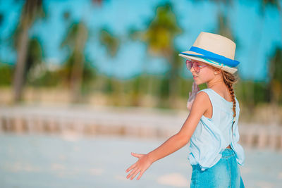 Side view of young woman wearing hat standing outdoors