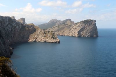 Scenic view of sea by mountains against sky