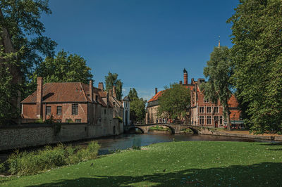 Old buildings next to canal and bridge with people in bruges. a town full of canals in belgium.