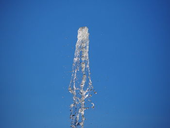 Low angle view of water splashing against blue sky