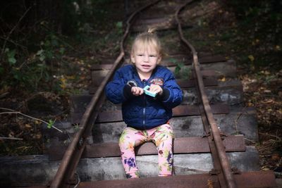 High angle view of cute baby girl sitting on railroad track