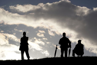 Silhouette father and son walking on field against sky