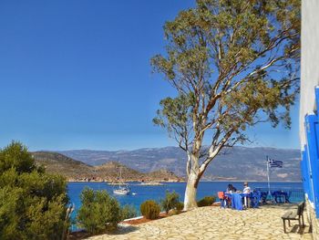 People sitting on beach against clear blue sky