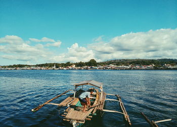 Man on outrigger boat sailing in sea 