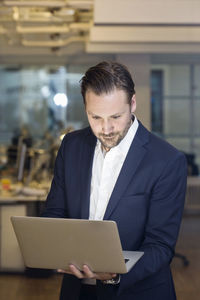 Mid adult businessman using laptop in office