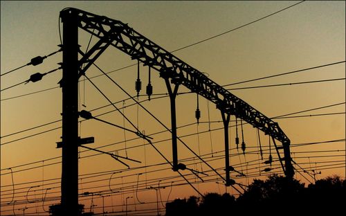 Low angle view of silhouette electricity pylon against sky during sunset