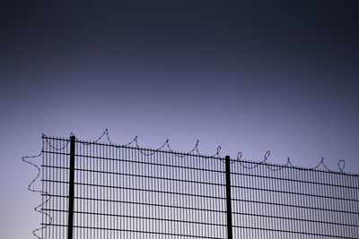 Low angle view of barbed wire on fence against clear sky