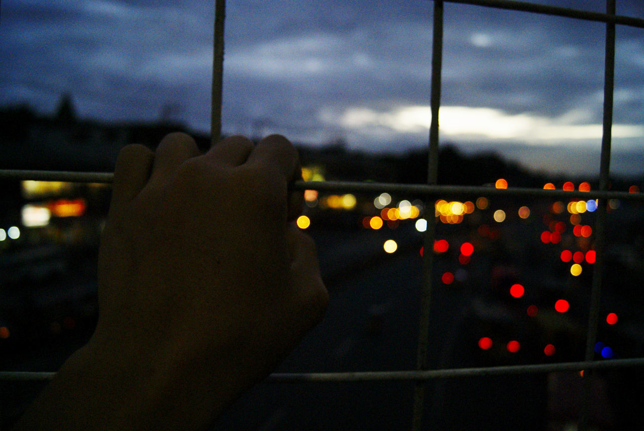 CLOSE-UP OF HAND AGAINST ILLUMINATED WINDOW