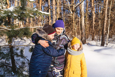 Happy mother and kids standing outdoors during winter