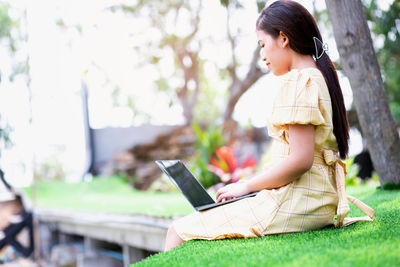 Side view of a girl looking away while sitting on grass