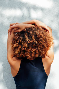 Rear view of woman with curly hair against wall