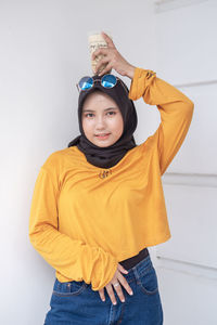 Portrait of young woman standing against wall