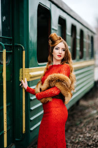 Portrait of young woman standing against wall