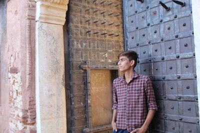 Portrait of young man standing against building