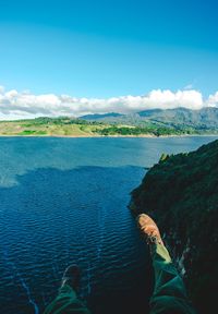 Low section of person by sea against sky