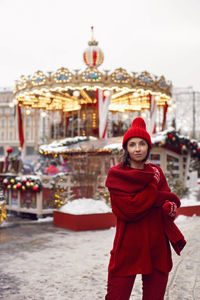 Woman in a red warm sweater, hat in winter, red square in moscow against the background carousel