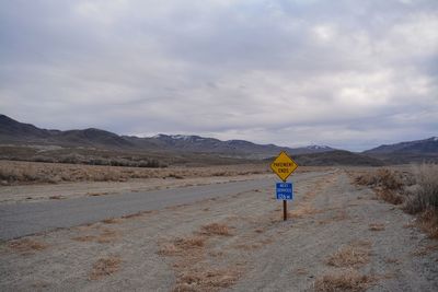 Road sign on road against sky