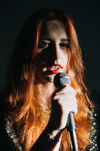 Portrait of redhead female singer woman in sparkly evening dress holding microphone. singer at