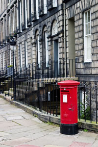 Red telephone booth by building in city