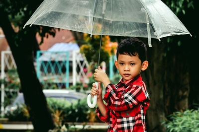 Portrait of boy holding umbrella during rainy season