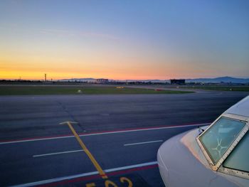 Airport runway against sky during sunset